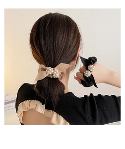 Détail de chouchous élégants en soie beige et noire avec perles sur une queue de cheval
