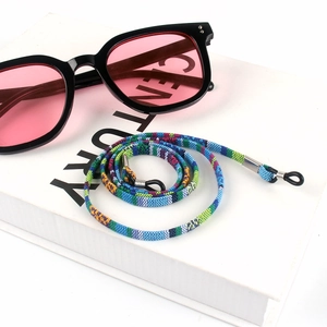 Detail shot of rainbow braided glasses strap with metal buckles on a white book decor