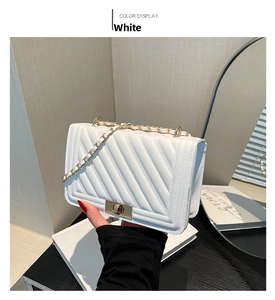 Detail of white quilted handbag with V-stitch pattern and gold chain strap