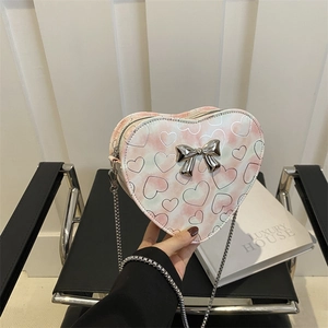 Pink heart-shaped crossbody bag with tie-dye pattern and metal bow on silver chain