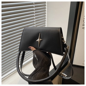 Détail du sac à bandoulière en cuir noir mat avec ornement métallique en forme d'étoile