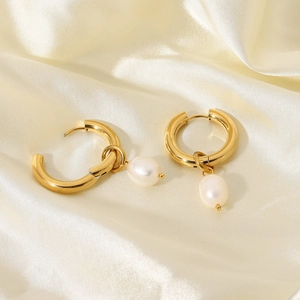 Detail of 18k gold plated hoop earrings with pearl charms on elegant beige silk fabric