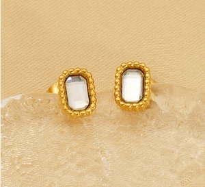 Détail macro de boucles d'oreilles vintage en or avec zircon carré et serti perlé
