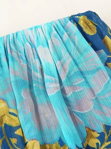 Detail of floral printed pleated chiffon fabric in bright sky blue and yellow tones