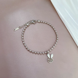 Dettaglio del bracciale a sfere in acciaio argento con ciondolo a coniglio e FÚ