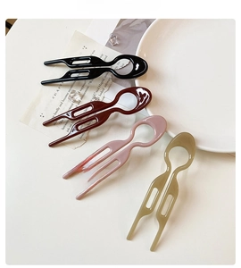 Close-up of four glossy U-shaped hair pins in black, burgundy, pink and grey-green