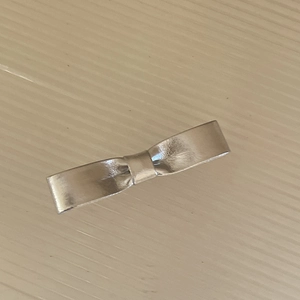 Dettaglio macro del fermaglio per capelli a fiocco argento con trama in ecopelle