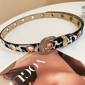 Ceinture léopard en cuir avec boucle dorée ovale et œillets posée sur un magazine Vogue