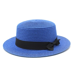 Detail of royal blue straw boater hat with flat top and black ribbon bow decoration