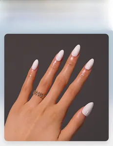Detail of glossy white almond press-on nails with a gold hollow rhinestone ring