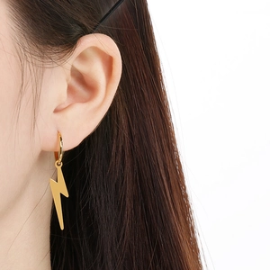 Detailed view of lightning bolt earrings in gold finish worn on a model's ear