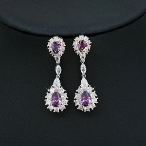 Macro view of silver bridal earrings featuring purple pear-shaped and white crystals
