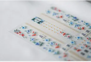 Macro shot of self-adhesive nail stickers with blue flowers and gold geometric lines