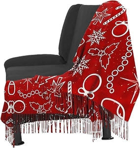 Detail of red Christmas pattern scarf with festive snowflakes and fringe hanging on a sofa