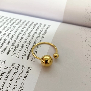 Detail view of gold geometric ring with dual polished metal spheres on open band
