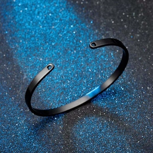 Macro detail of a black stainless steel C-shaped open cuff bracelet on a starry background