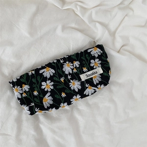 Close-up of black cotton-linen makeup bag with white daisy floral embroidery detail