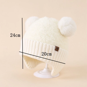 Dettaglio cappello neonato in maglia bianca con due pompon e patch zampa, 24x20cm