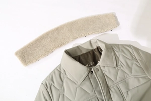 Detailed close-up of quilted winter jacket with removable faux fur collar and snap buttons
