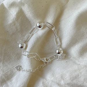 Macro detail of 925 sterling silver beaded bracelet with heart charm on fabric