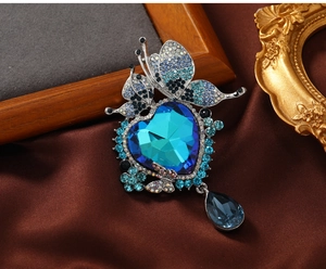 Detailed view of luxury heart blue crystal brooch with butterfly and tassel drop on silk