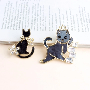 Chic cat-shaped brooches with black marble finish and zircon accents on a vintage book
