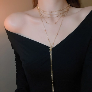 Macro detail of multi-layered gold cross necklace with delicate bead chain on model