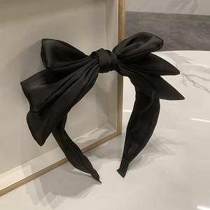 Detail of elegant black satin triple-layered bow headband on marble background