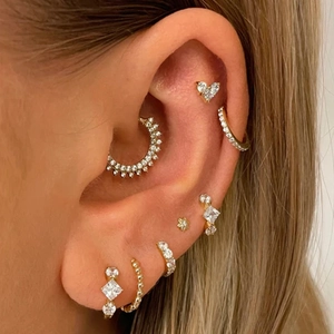 Close-up of gold S925 silver heart earrings and cubic zirconia ear cuffs set on ear