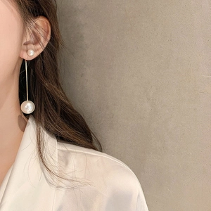 Close-up of elegant long tassel pearl earrings featuring a sleek gold bar drop on model