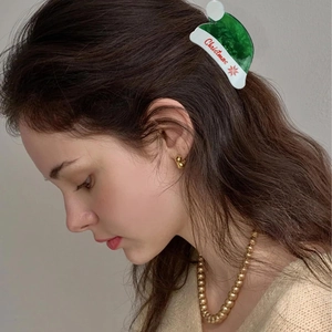 Detail showing a green Christmas hat hair claw clip with snowflake pattern and text
