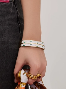 Detail of white enamel evil eye bangle bracelets with gold trim on model wrist