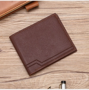 Close-up of brown leather wallet with lychee texture and fine stitching on wooden desk