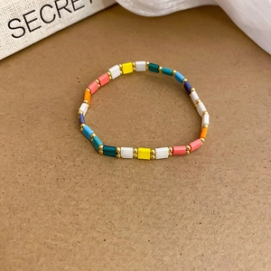 Close-up of colorful beaded star bracelet with gold spacers on textured background