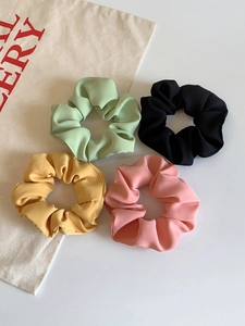 Detail of four matte scrunchies in mint green, ginger, pink, and black colors