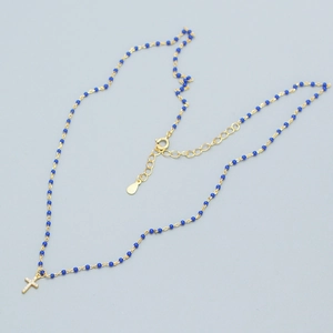 Detail of gold beaded necklace featuring a sparkling diamond-set cross pendant with blue beads