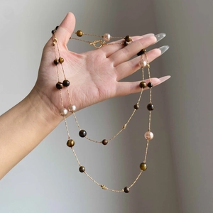 Detail of tiger eye stone and pearl necklace with golden chain and T-bar toggle clasp