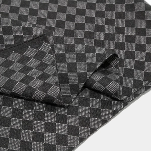 Detail view of winter knitted scarf featuring black and grey checkerboard pattern textures
