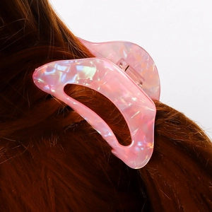 Pince à cheveux rose irisée pour femme présentée sur une chevelure brune élégante