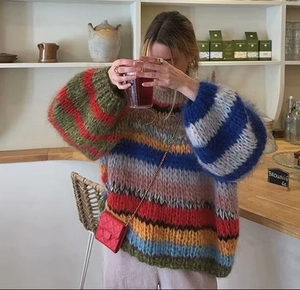 Close-up of rainbow striped mohair sweater with fluffy texture and red quilted bag