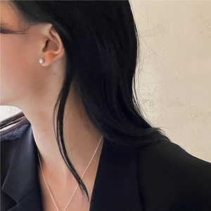Close-up of 925 sterling silver brushed round bead earrings and fine necklace on model