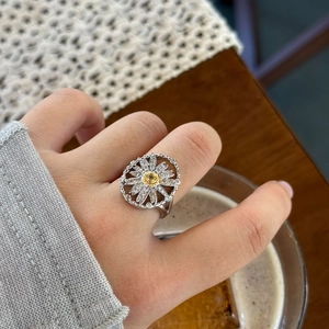 Detail of silver daisy ring with yellow gemstone and clear zirconias on model hand