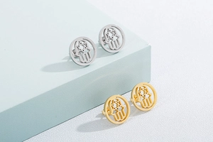 Detail of gold and silver Hamsa earrings with hollow Star of David design on blue stands