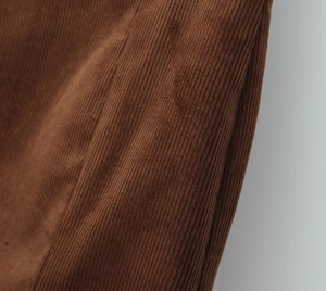 Close-up macro view of the brown corduroy fabric texture and ribbed pattern on the skirt