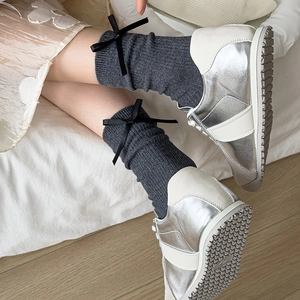 Detail of dark grey knit socks featuring delicate black bow accents and lace trim