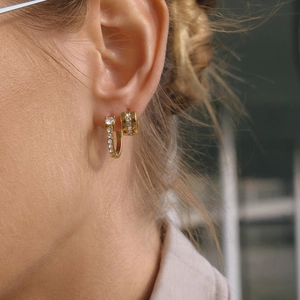 Close-up of gold stainless steel hoop earrings with clear cubic zirconia on a model's ear