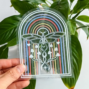 Close-up of rainbow prism suncatcher sticker with moth and mushroom designs