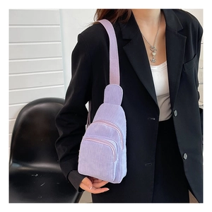 Detailstruktur der lila Cord-Umhängetasche, getragen über einem schwarzen Blazer