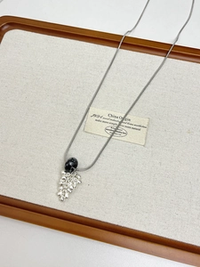 Détail du collier à chaîne serpent argentée avec perle noire et pendentifs en forme de larmes