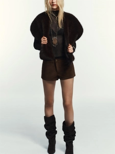 Detail shot of winter faux fur vest texture paired with black sheer knit top and brown shorts